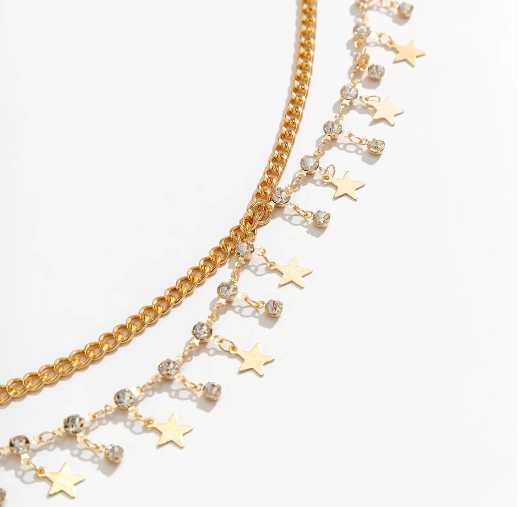 Flat lay of gold belly chain featuring star charms and rhinestones – stylish pole dancing gift or fitness accessory.